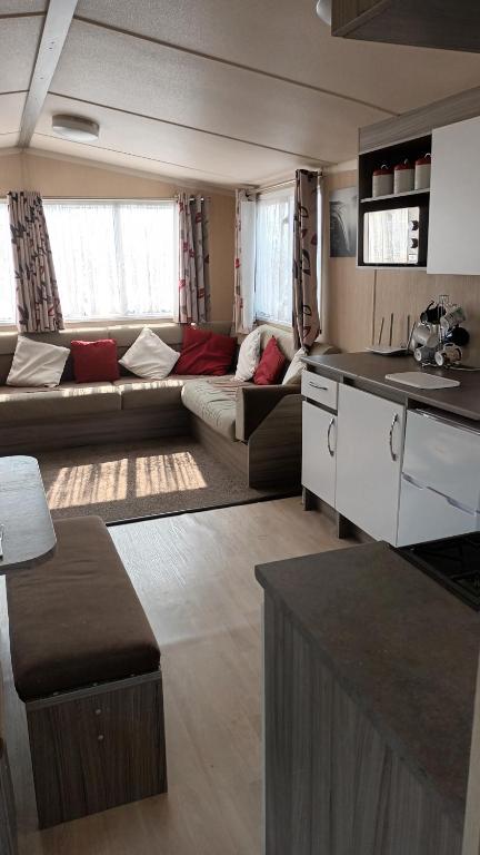 a large living room with a couch and a kitchen at 3 BEDROOM CARAVAN ON ST OSYTH BEACH HOLIDAY PARK WITH FREE Wfi AND PARKING in Saint Osyth