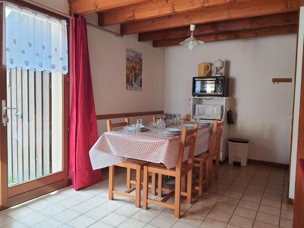 une salle à manger avec une table et des chaises et une cuisine dans l'établissement Chalet cosy 4/5 personnes avec jardins, parking, proche télécabine, navette gratuite - FR-1-401-228, à Cauterets