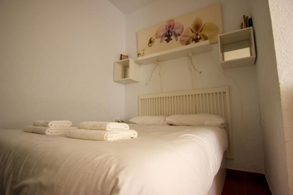 een slaapkamer met een wit bed en handdoeken bij RentalSevilla Enjoy Seville in Sevilla