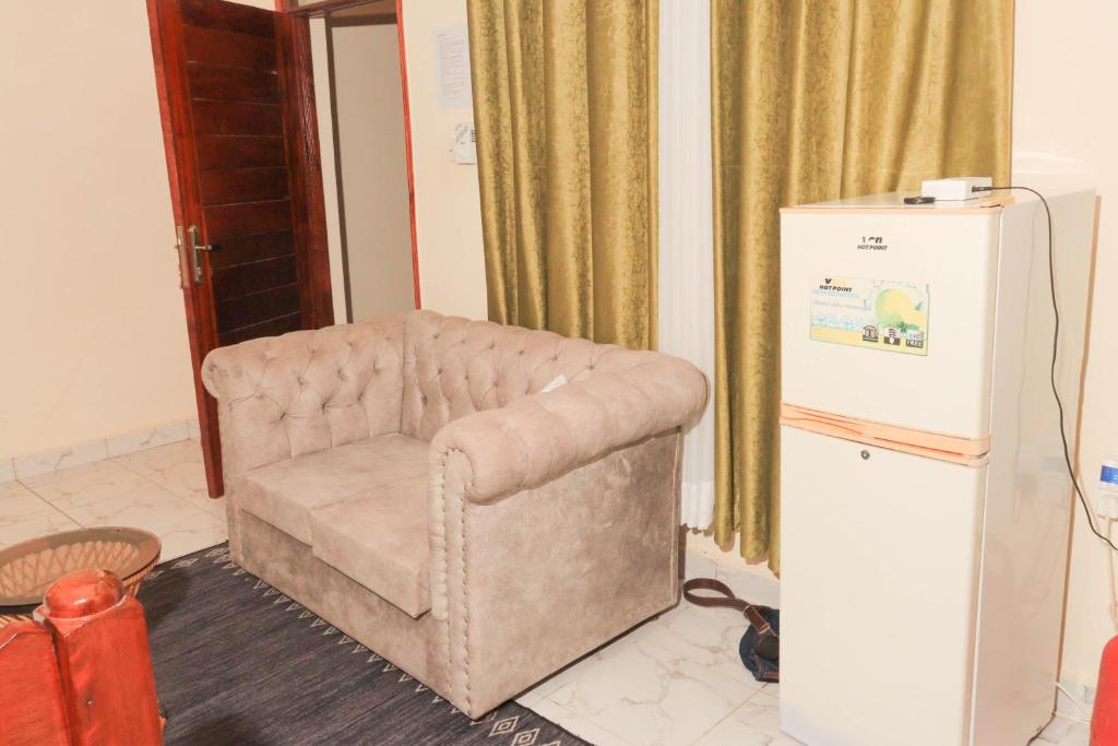 ein Wohnzimmer mit einem Stuhl und einem Kühlschrank in der Unterkunft AMELIA BNBS in Mtwapa