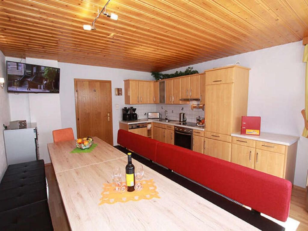 a kitchen with a red couch and a table with a bottle of wine at Apartment Miramonte-2 by Interhome in Kappl