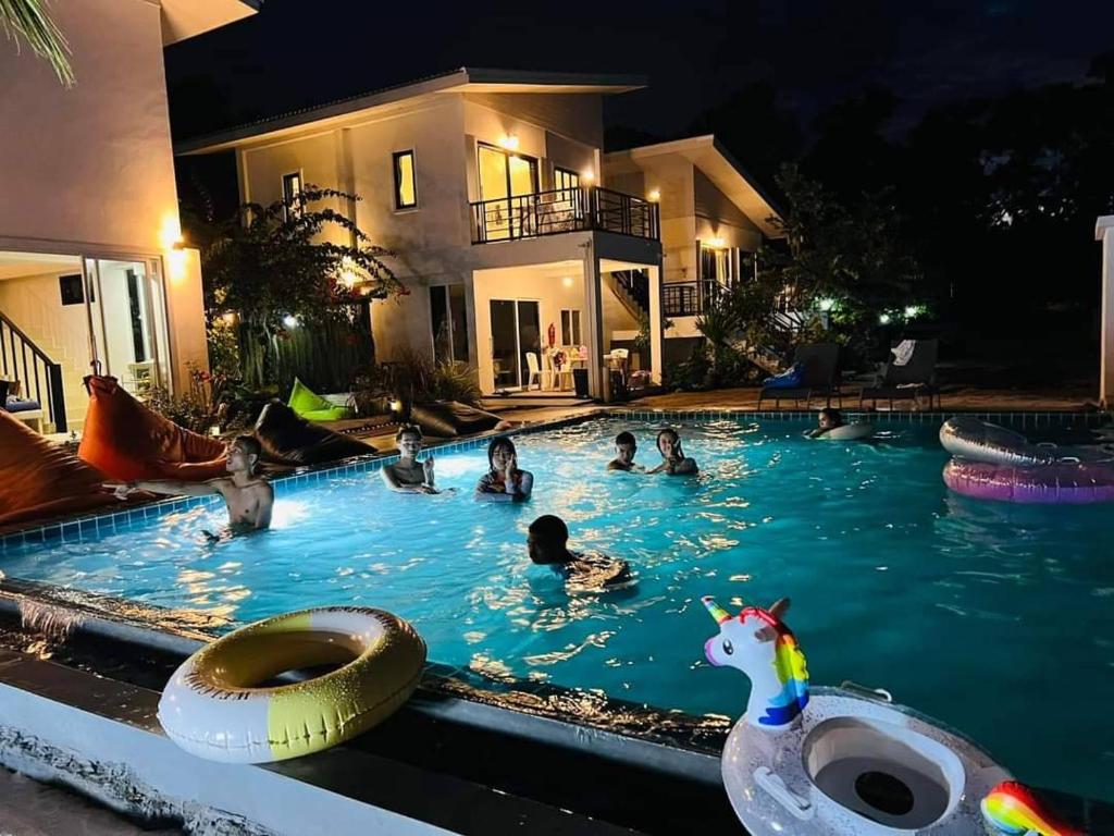 um grupo de pessoas em uma piscina à noite em Cozy Khanom โคซี่ ขนอม em Ban Na Dan