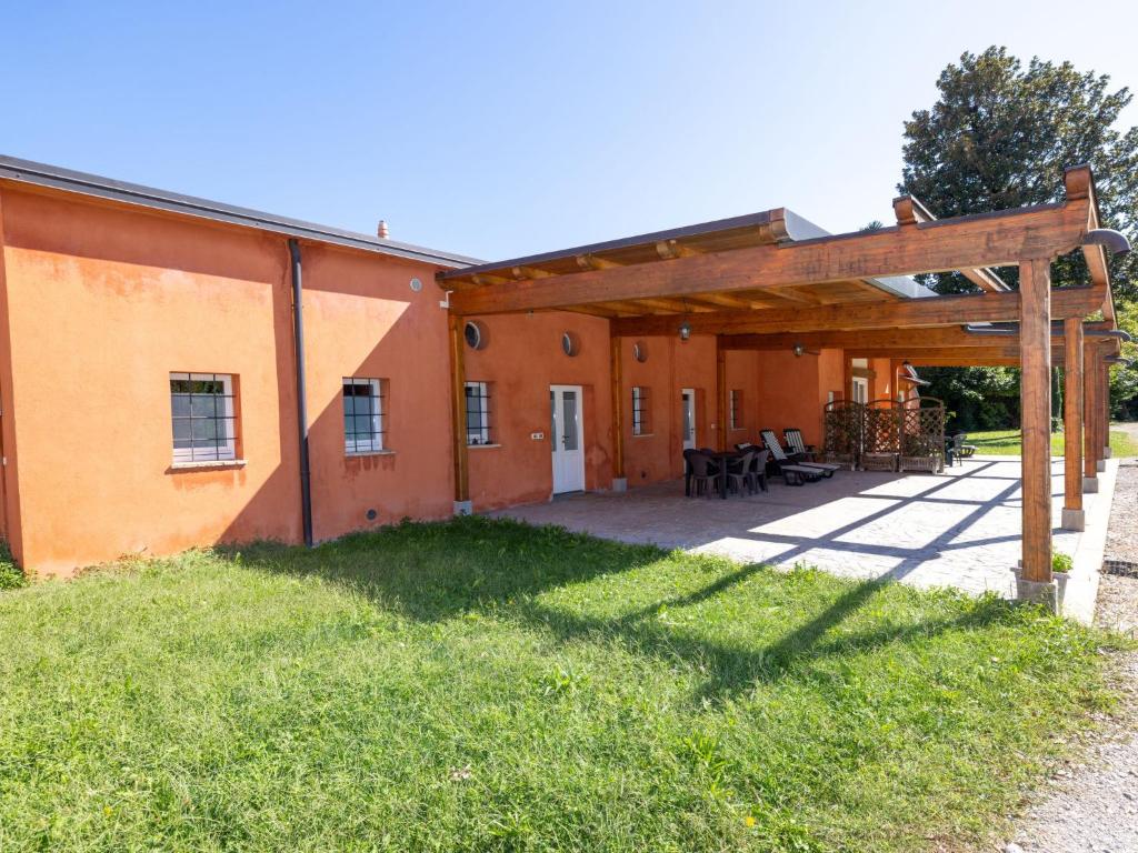 un bâtiment orange avec une terrasse en gazon dans l'établissement Apartment Winery Villa Vitas Dépendance - App-2 by Interhome, à Strassoldo