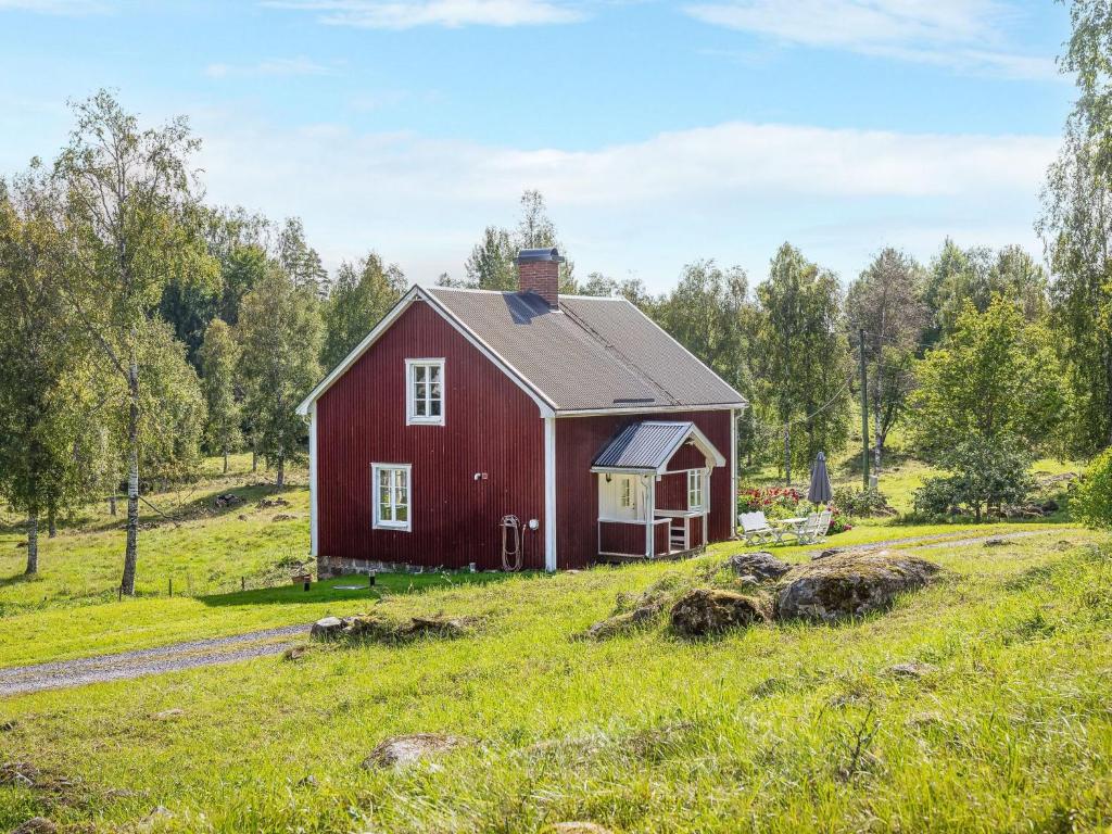 a red barn on a grassy hill with trees at Chalet Långban - VMD233 by Interhome in Filipstad