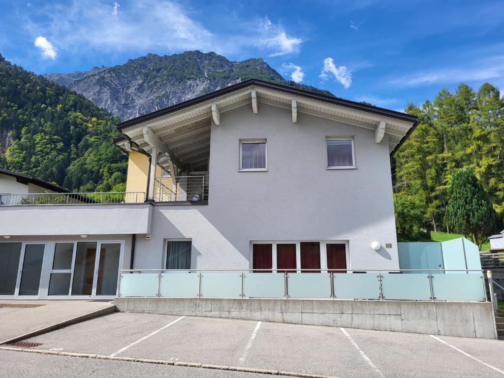 a white building with a balcony with mountains in the background at Apartment Living House Vandans by Interhome in Vandans