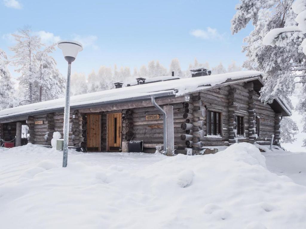 Holiday Home Rukakämmekkä by Interhome في روكا: كابينة خشبية في الثلج مع عمود خفيف