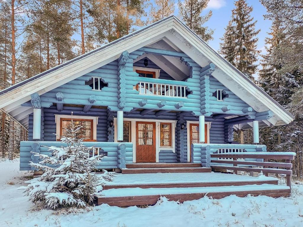 uma cabana de madeira azul com neve no chão em Holiday Home Päivärinne by Interhome em Mäkisauru