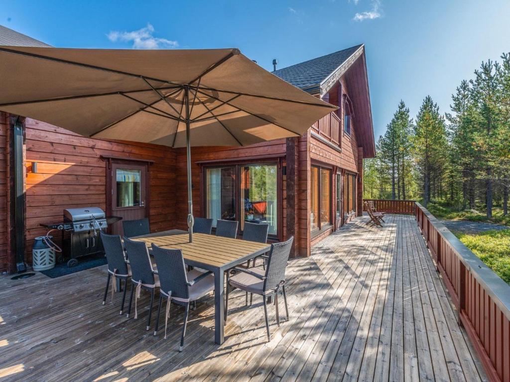 eine Holzterrasse mit einem Tisch, Stühlen und einem Sonnenschirm in der Unterkunft Holiday Home Lapinukonkäännös - incl- 1 ski pass by Interhome in Ruka