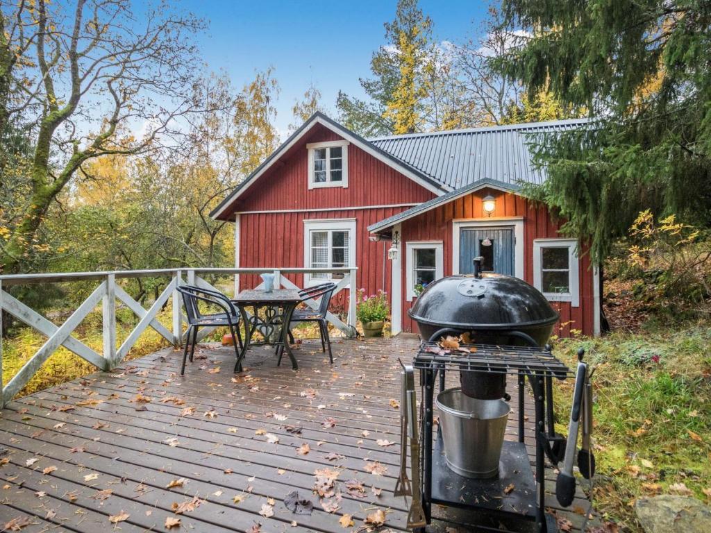 a grill on a deck in front of a red house at Holiday Home Puutarhurin mökki by Interhome in Tallnäs