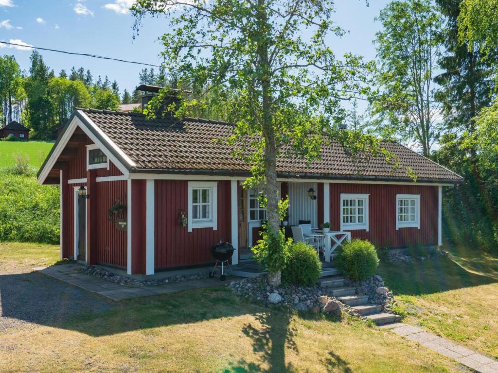 HirsjärviにあるHoliday Home Peukaloinen by Interhomeの庭の木のある赤いコテージ
