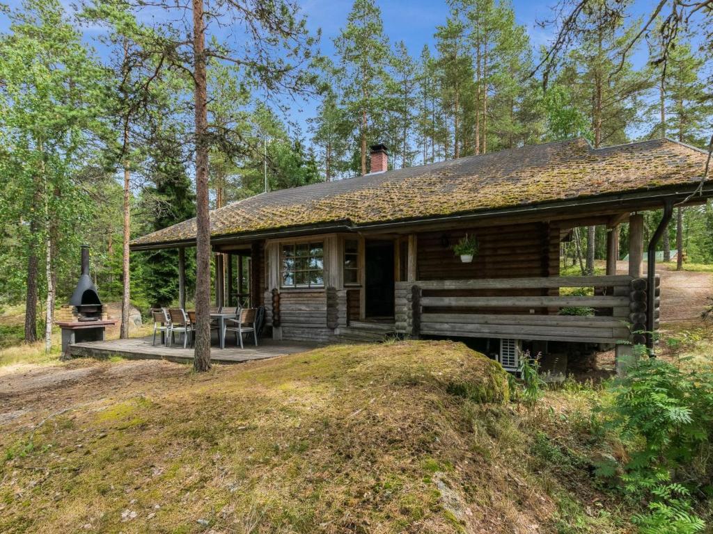 une cabane en rondins avec une terrasse couverte dans les bois dans l'établissement Holiday Home Elimäki by Interhome, à Heinjoki