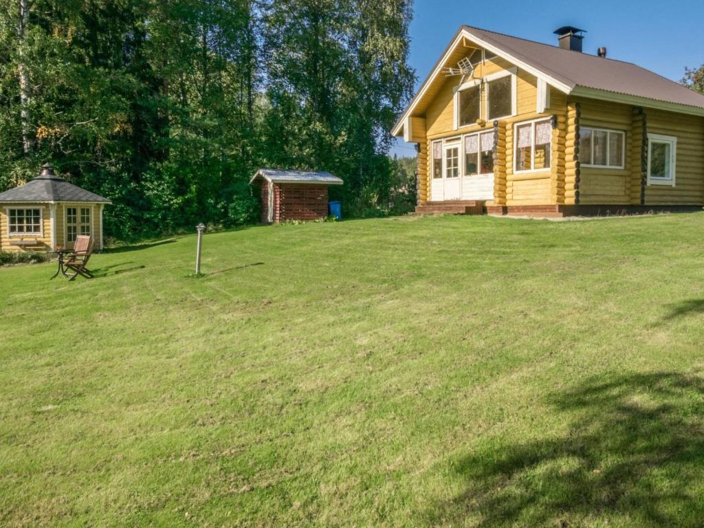 une maison jaune sur une cour herbeuse avec un bâtiment dans l'établissement Holiday Home Ahvenranta by Interhome, à Kosula