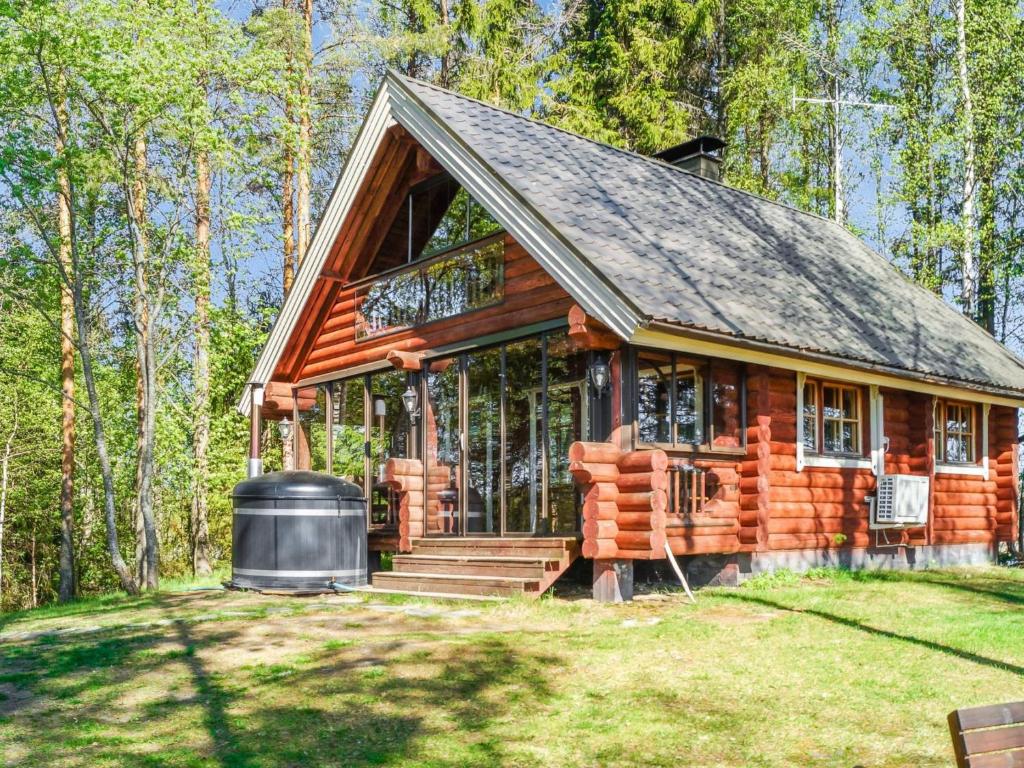 eine Blockhütte im Wald mit einem großen Fenster in der Unterkunft Holiday Home Huvilakoti 1 by Interhome in Puromäki