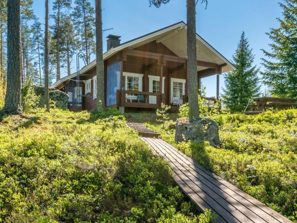 a house in the woods with a wooden walkway to it at Holiday Home Pajulintu by Interhome in Tiitanvaara