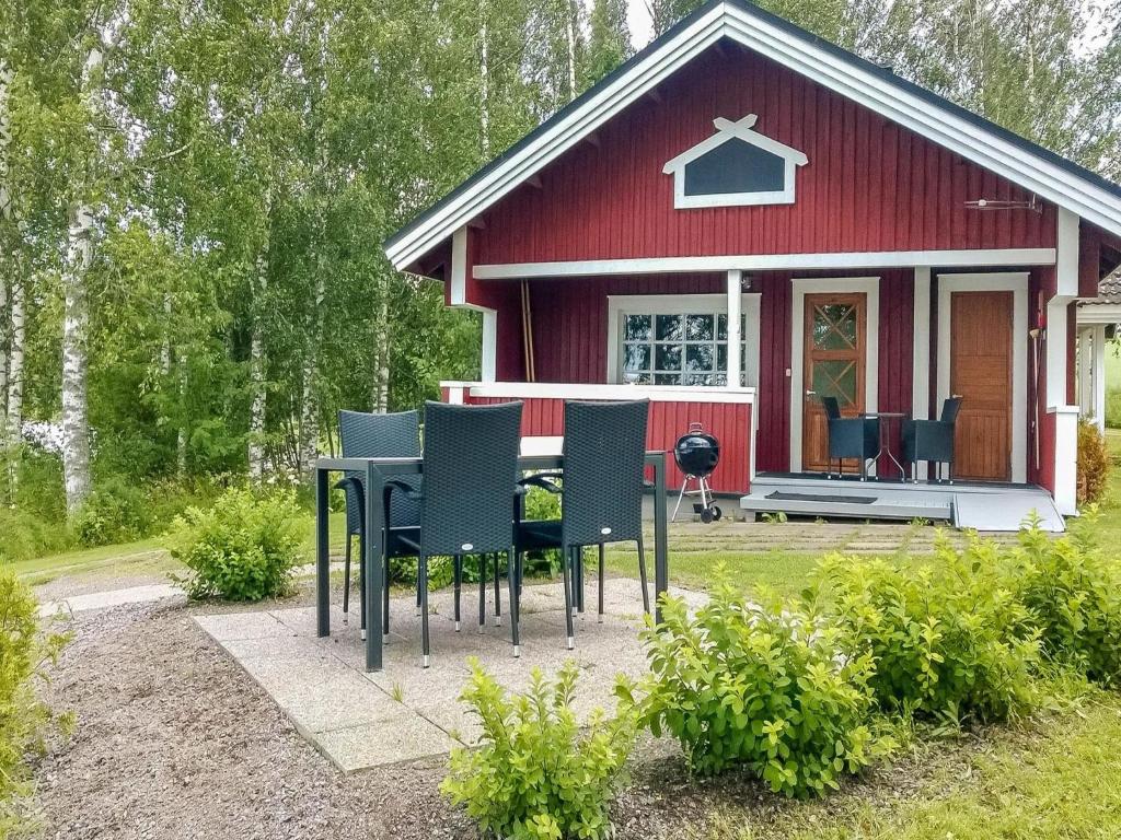 a red house with chairs and a table in front of it at Holiday Home Peltosirkku by Interhome in Hirsjärvi