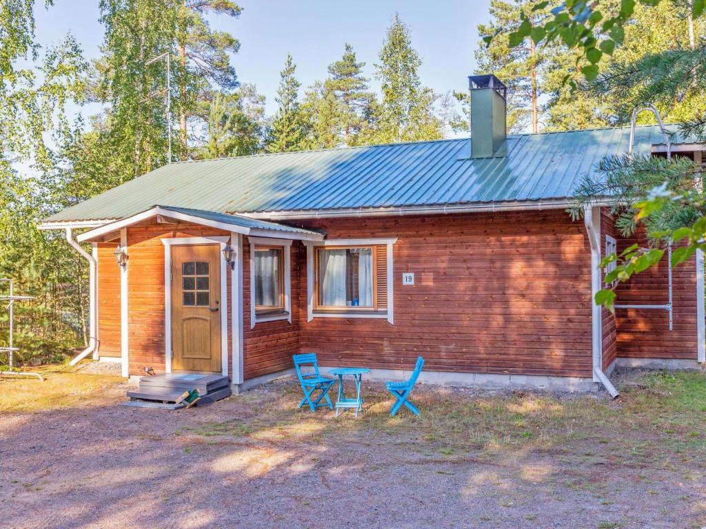 een klein huis met twee blauwe stoelen ervoor bij Holiday Home Kettukallio by Interhome in Luhtanen