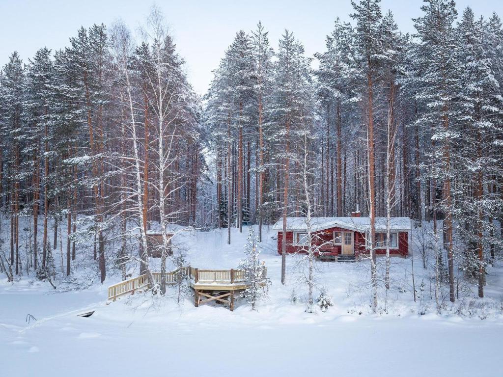 a cabin in a snow covered forest with trees at Holiday Home Ainola by Interhome in Huuhanaho