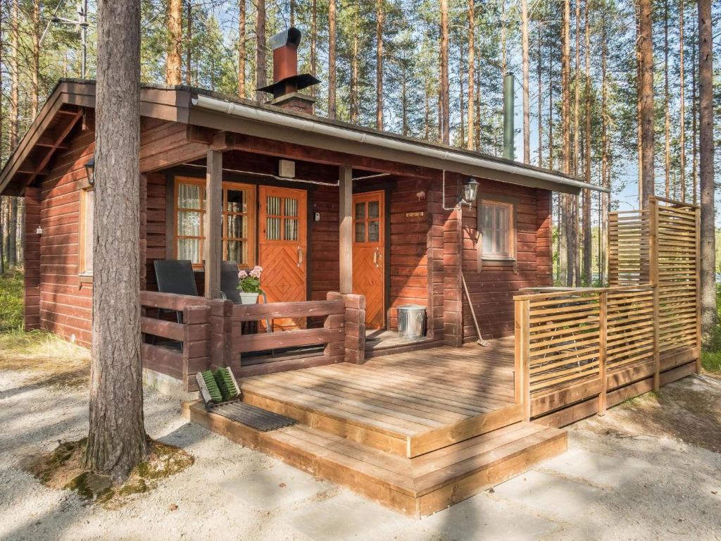 une cabane en rondins avec une terrasse dans les bois dans l'établissement Holiday Home Puolukka by Interhome, à Herttua
