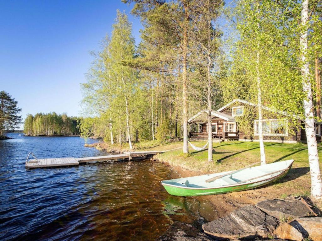 a boat on the shore of a lake with a cabin at Holiday Home Tatunmökki by Interhome in Huuhanaho