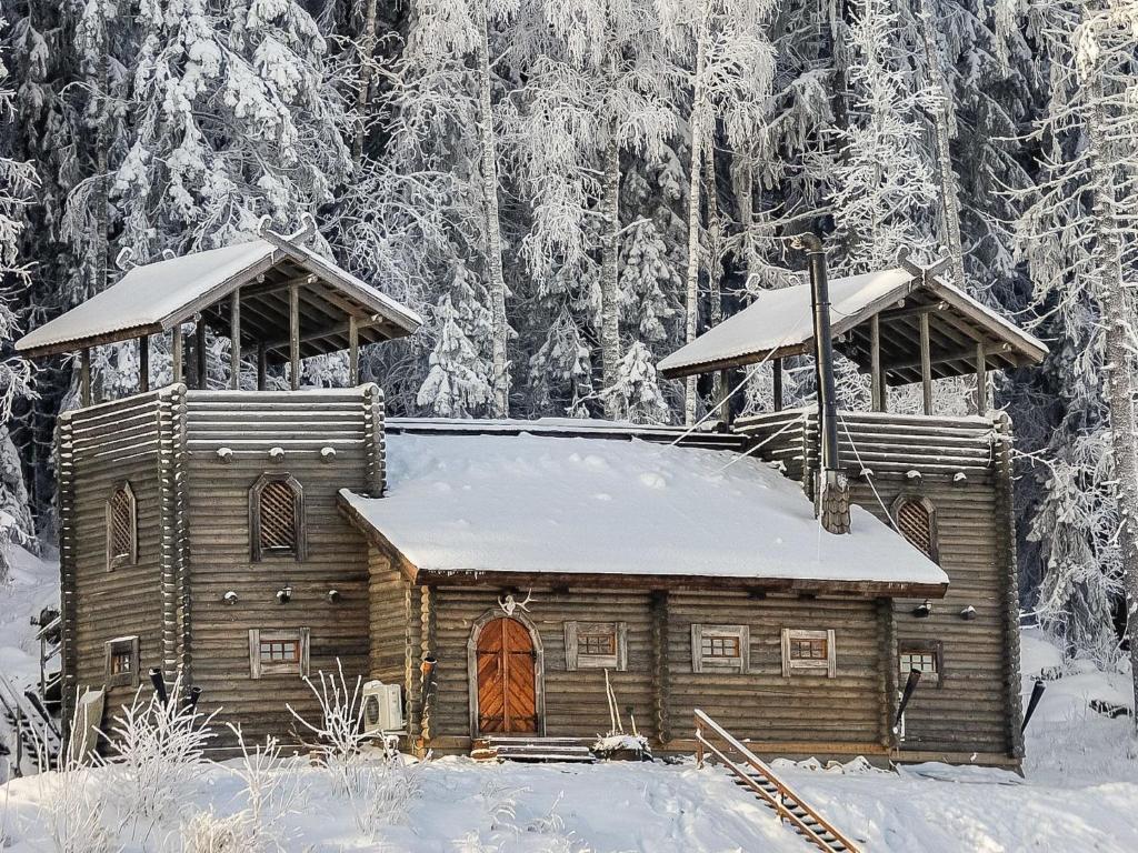 a wooden cabin in the snow with snow covered trees at Holiday Home Härkälinna by Interhome in Hauho