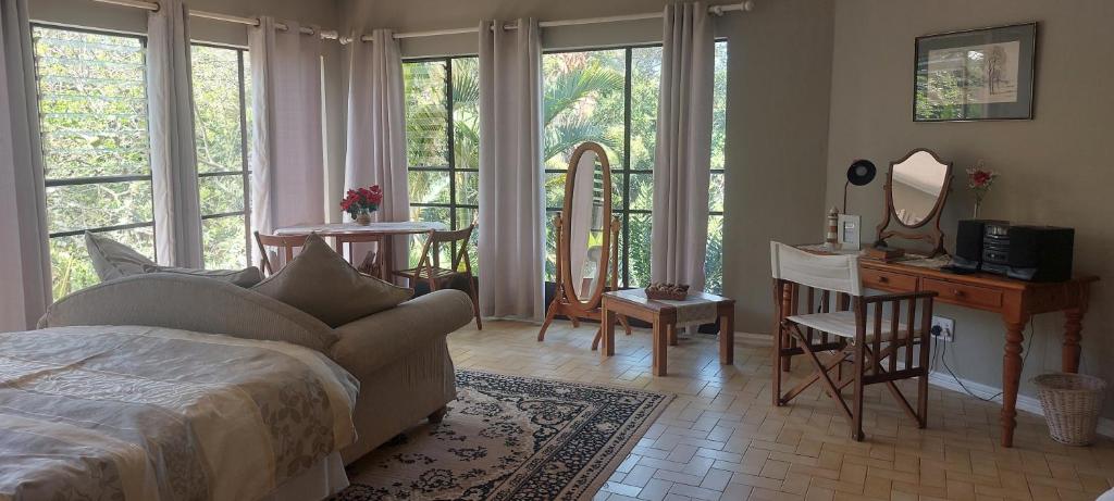 een slaapkamer met een bed en een bureau met een spiegel bij Cycasia Lodge in Umzumbe