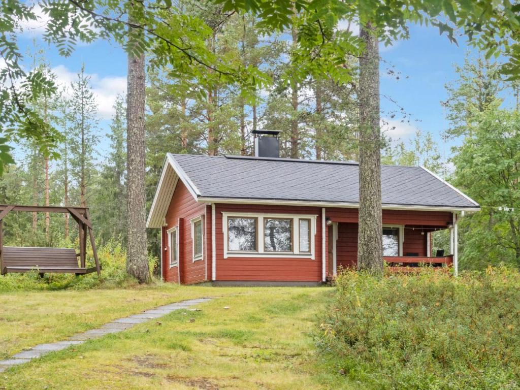 uma pequena cabana vermelha na floresta com um banco em Holiday Home Lepokunnas by Interhome em Suomussalmi