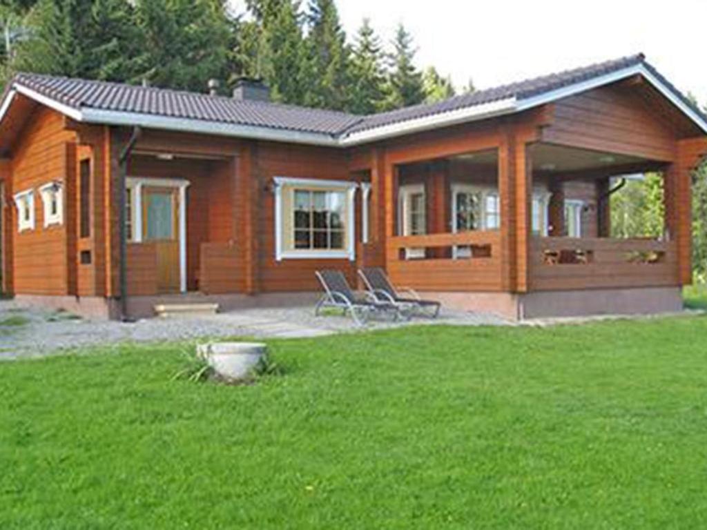uma casa de madeira com duas cadeiras num quintal em Holiday Home Koivuranta by Interhome em Sipsiö