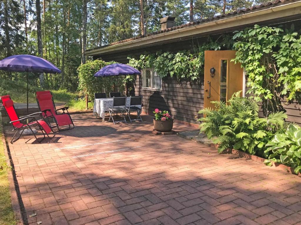 um pátio com cadeiras e guarda-sóis em frente a uma casa em Holiday Home Ranta-iivari by Interhome em Lohja