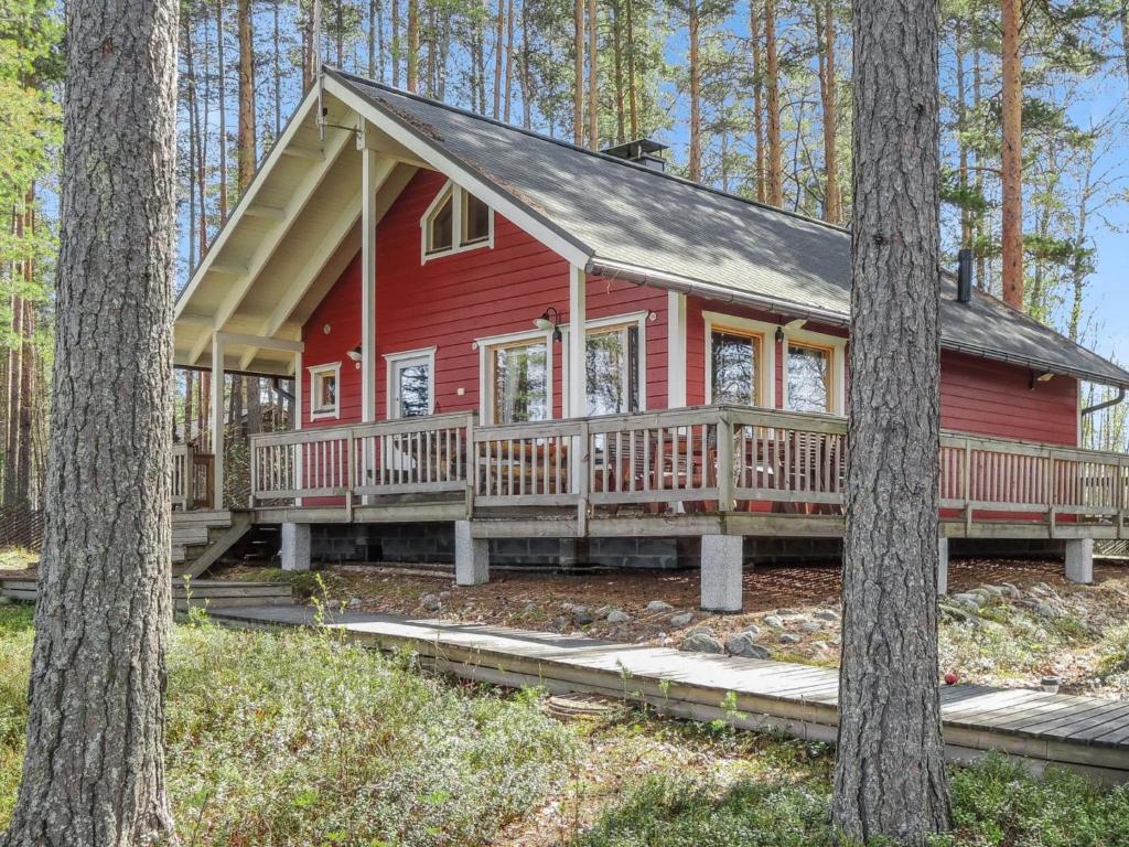 une cabine rouge dans les bois avec des arbres dans l'établissement Holiday Home Sammonranta by Interhome, à Kolinkylä