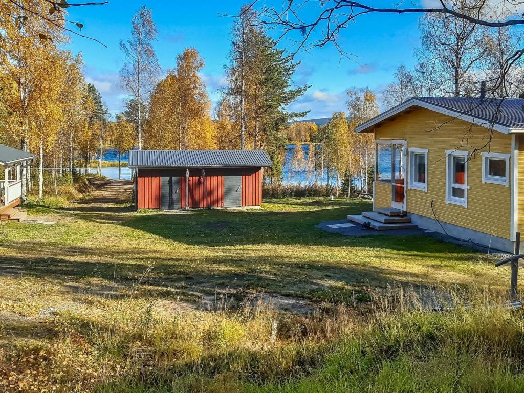 a home with a yellow and red house in a field at Holiday Home Huitsin nevada by Interhome in Kangosjärvi