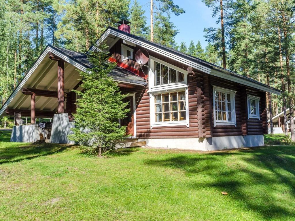 a small log cabin with a man on the roof at Holiday Home Honkakoli 3 by Interhome in Hattusaari