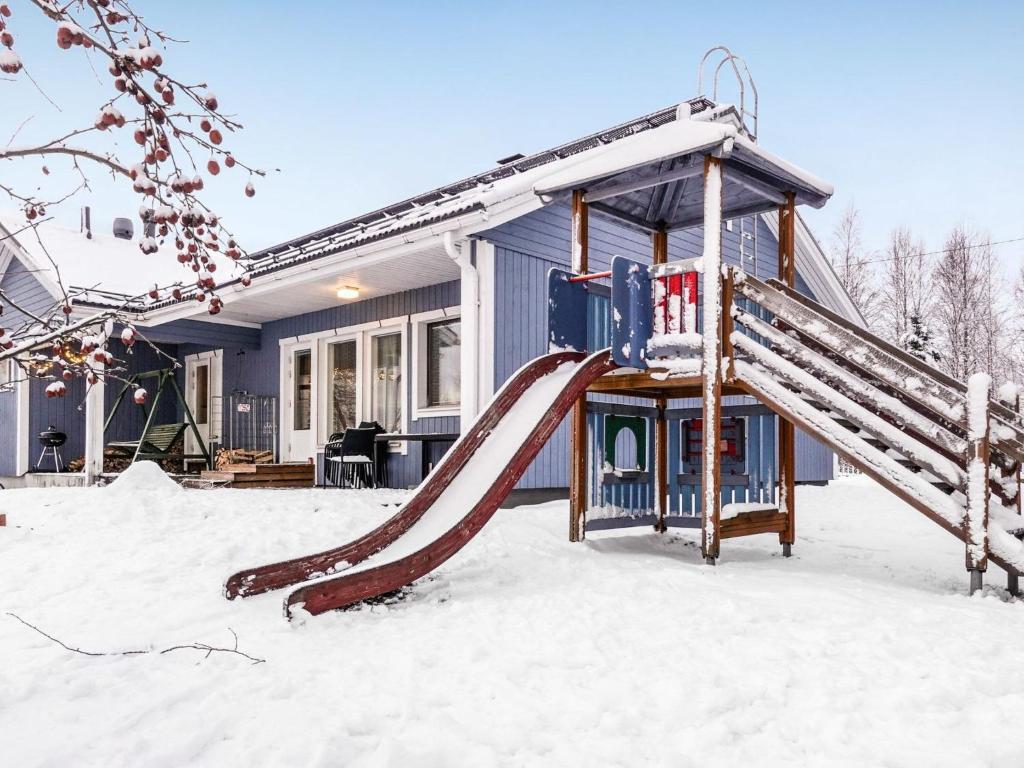 a playground in the snow in front of a house at Holiday Home Villa lehmus by Interhome in Rovaniemi
