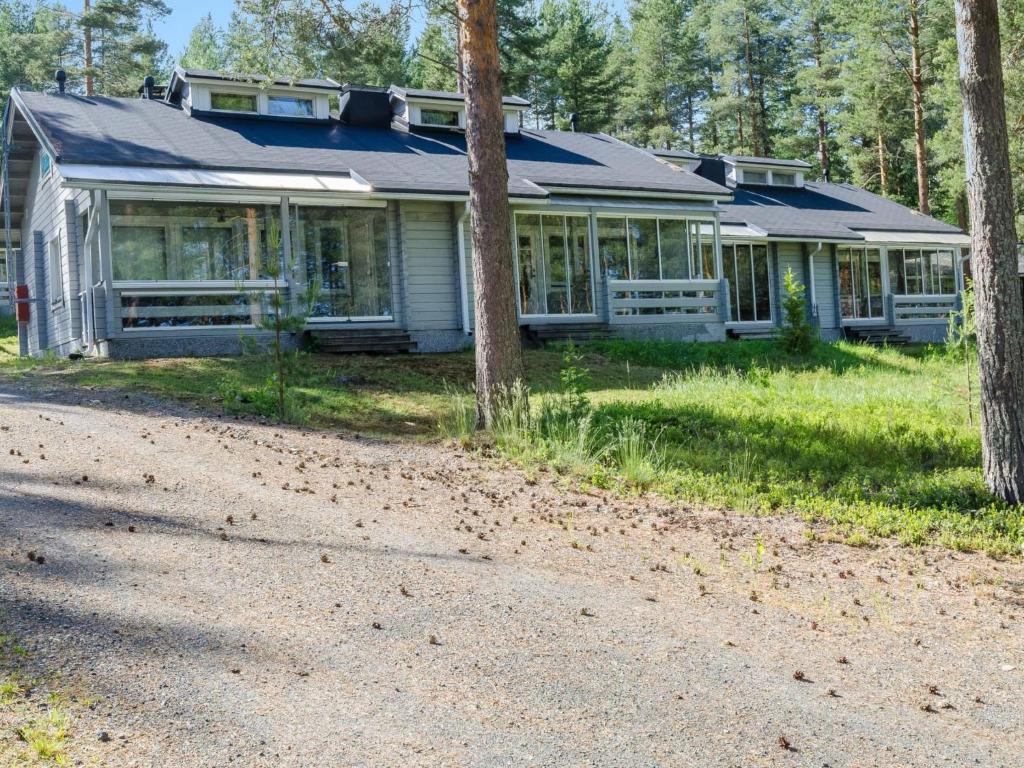 una casa en el bosque con un camino de grava delante de ella en Holiday Home Karjalan heili 17 by Interhome, en Kolinkylä