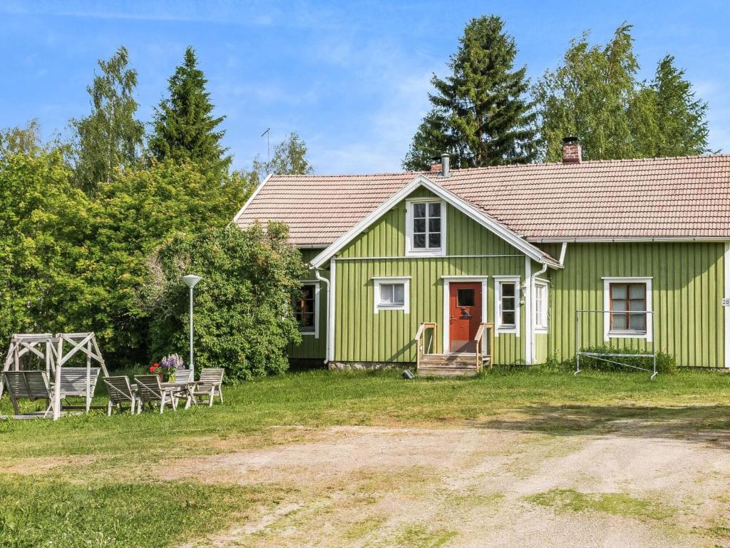 a green house with a red door in the yard at Holiday Home Palokärki by Interhome in Urimolahti