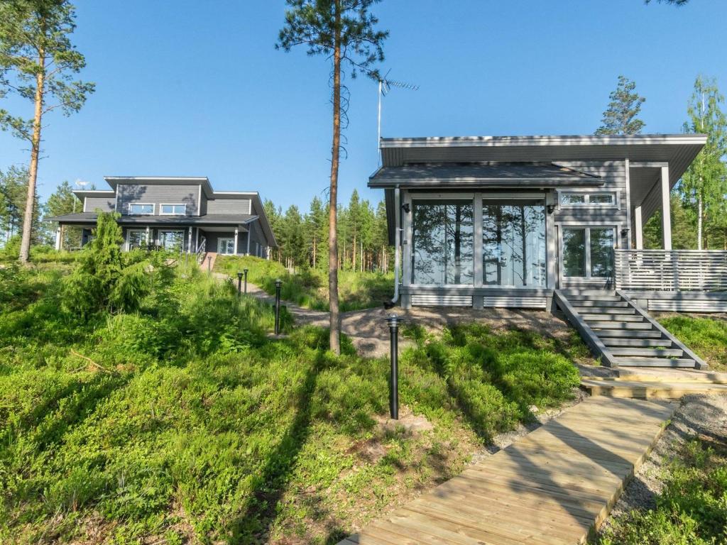 a house in the woods with a wooden walkway leading to it at Holiday Home Villa saunaniemi i by Interhome in Selänpää