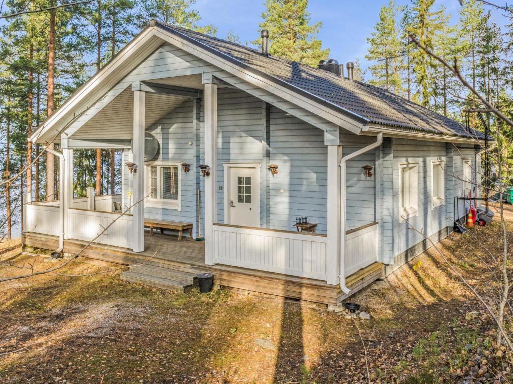 une maison blanche avec une terrasse couverte dans les bois dans l'établissement Holiday Home Kainaloranta by Interhome, à Kolinkylä