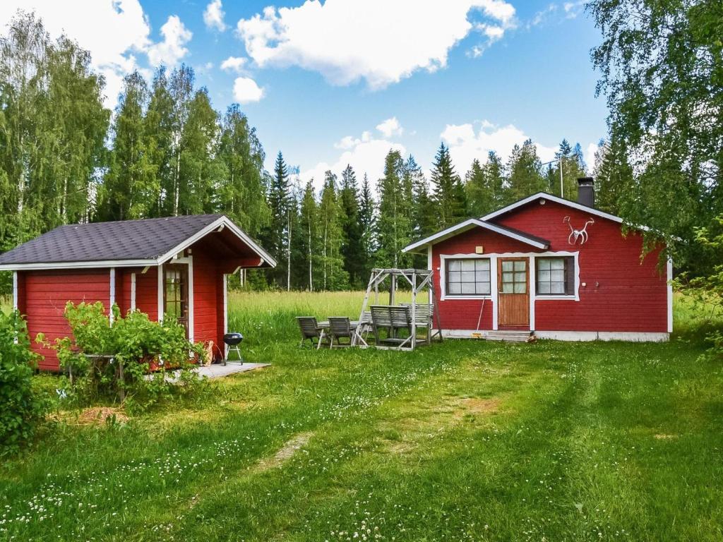 una casa roja con un parque infantil en un campo en Holiday Home Pihalintu by Interhome, en Heikkilä