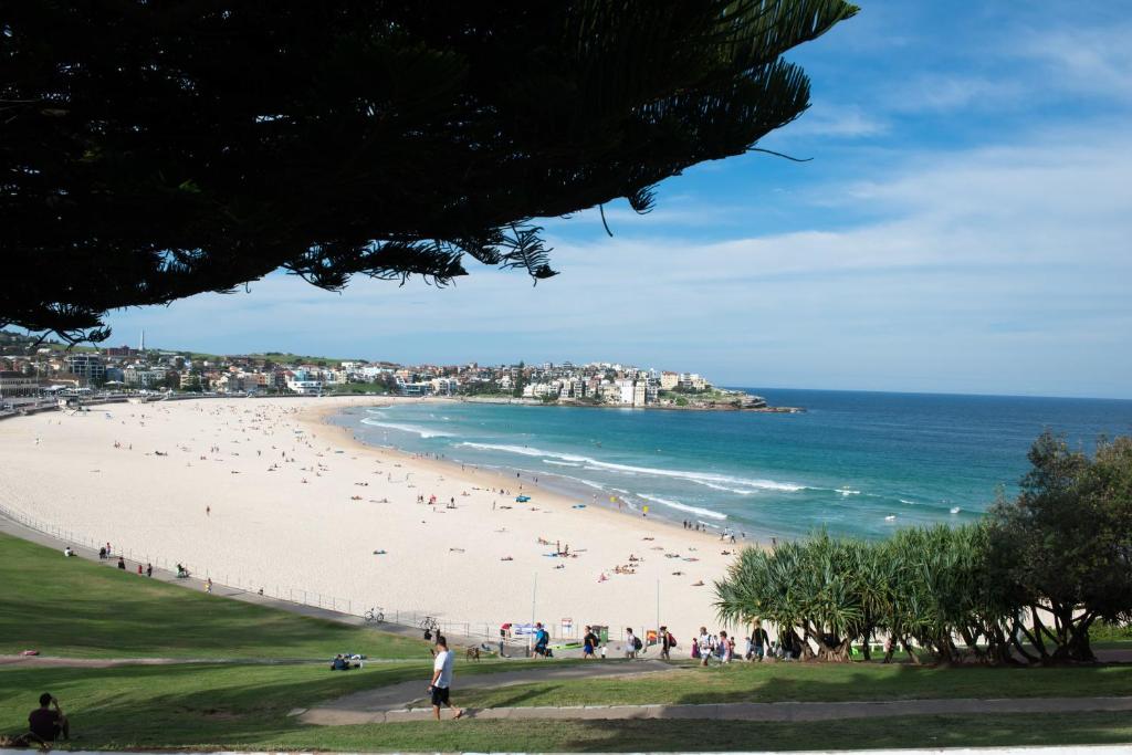 a beach with many people walking on it at Bondi 38 Serviced Apartments in Sydney