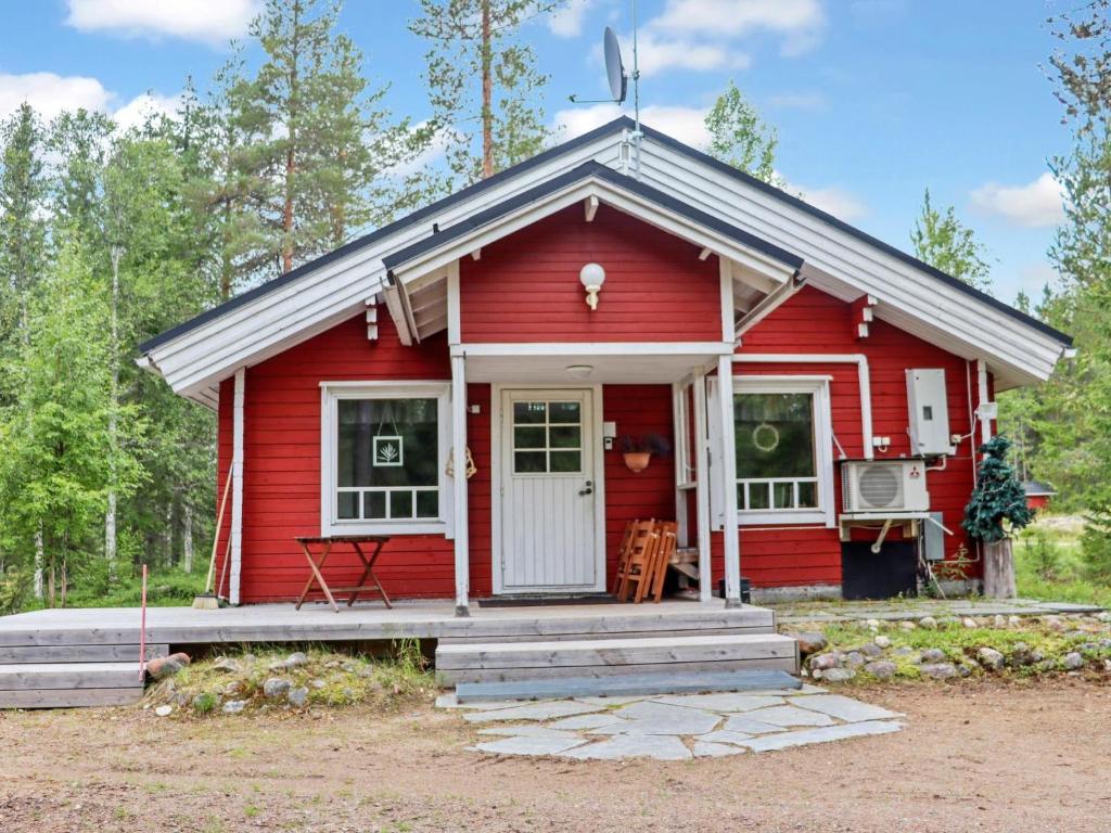 a red tiny house in the woods with a porch at Holiday Home Hyryn herra cottage by Interhome in Hyrynsalmi