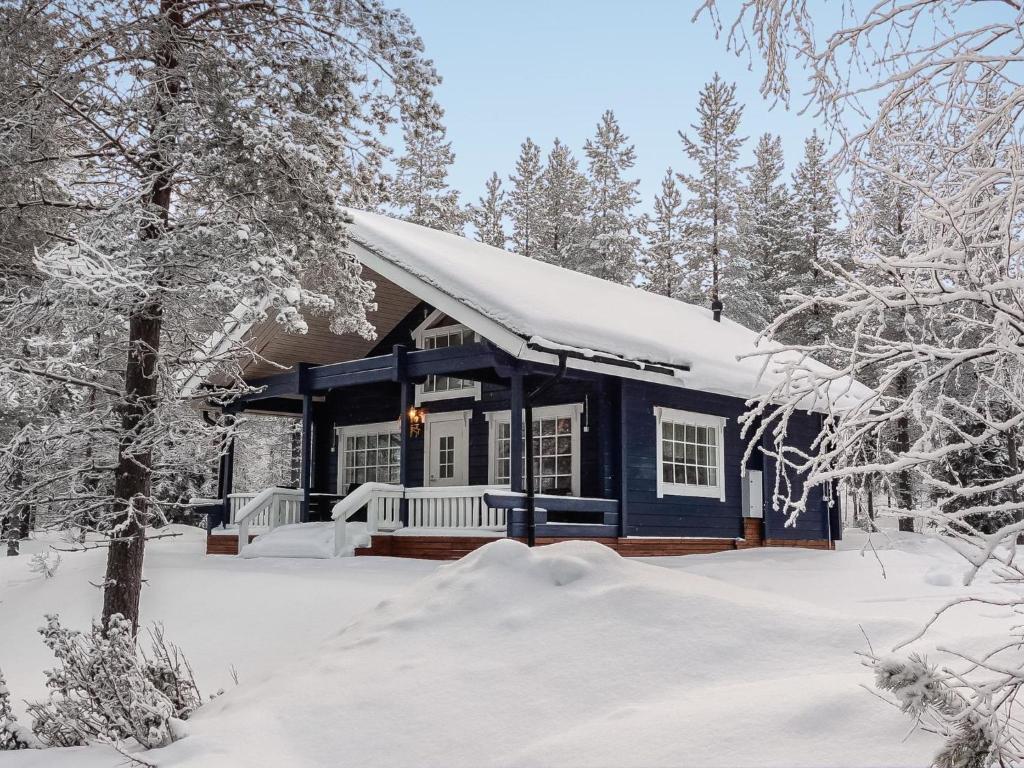 uma cabana azul na neve com árvores cobertas de neve em Holiday Home Keselmäkangas by Interhome em Tikkala