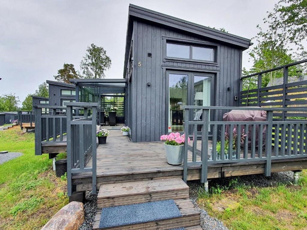 a gray cabin with a wooden deck with flowers at Holiday Home Willa anna b by Interhome in Dragsfjärd