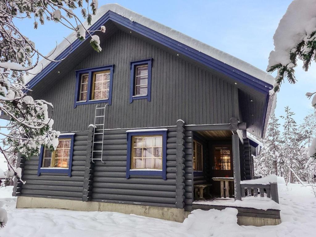 uma cabana de madeira com janelas azuis na neve em Holiday Home Lomapykälä 1 a by Interhome em Sirkka