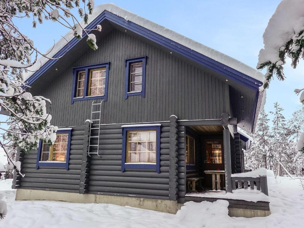 une cabane en rondins dotée de fenêtres bleues dans la neige dans l'établissement Holiday Home Lomapykälä 1 a by Interhome, à Levi