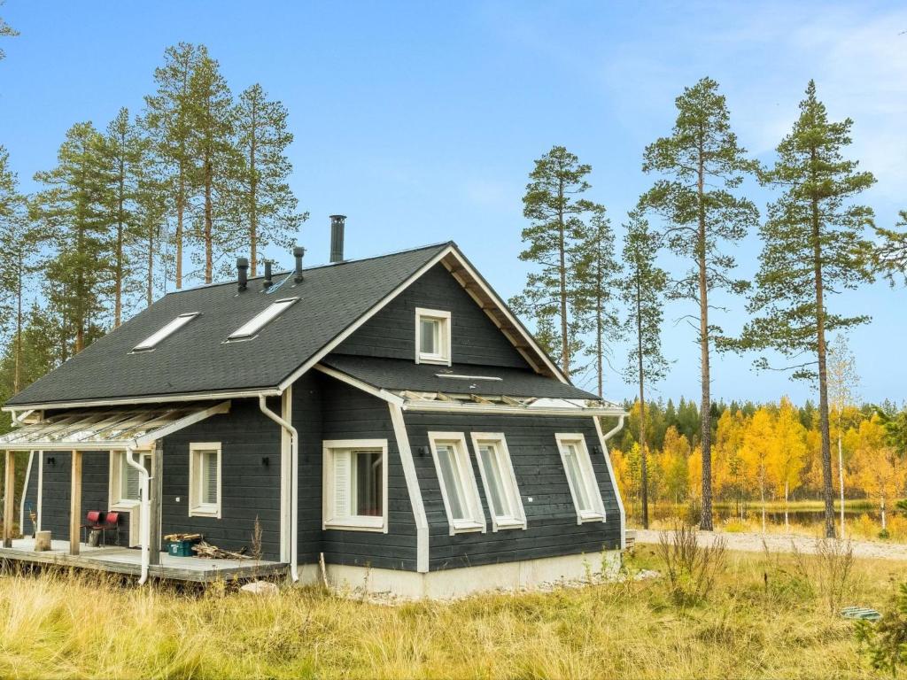 a black house in a field with trees at Holiday Home Aurora by Interhome in Narkaus
