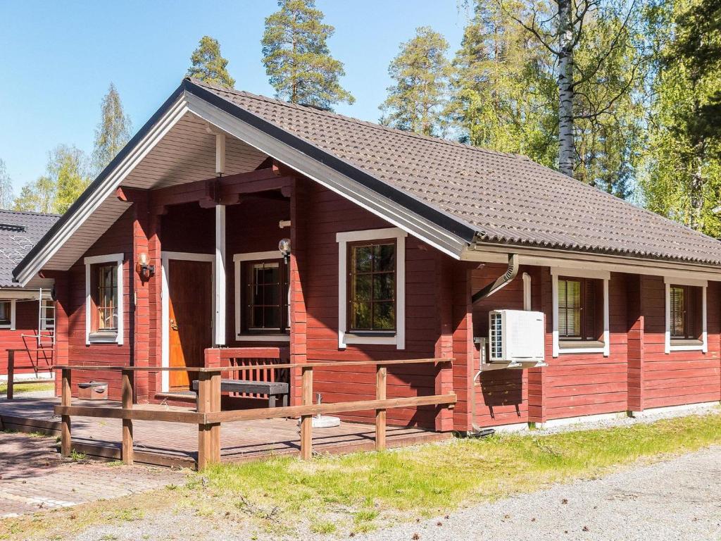 a small red house with a wooden porch at Holiday Home Lomasyväri 810 by Interhome in Nilsiä