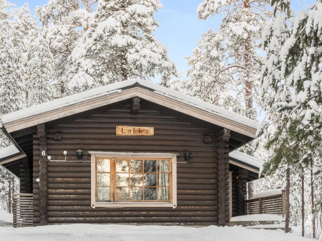 Una cabaña de madera en la nieve con un cartel. en Holiday Home Lakka by Interhome en Salla