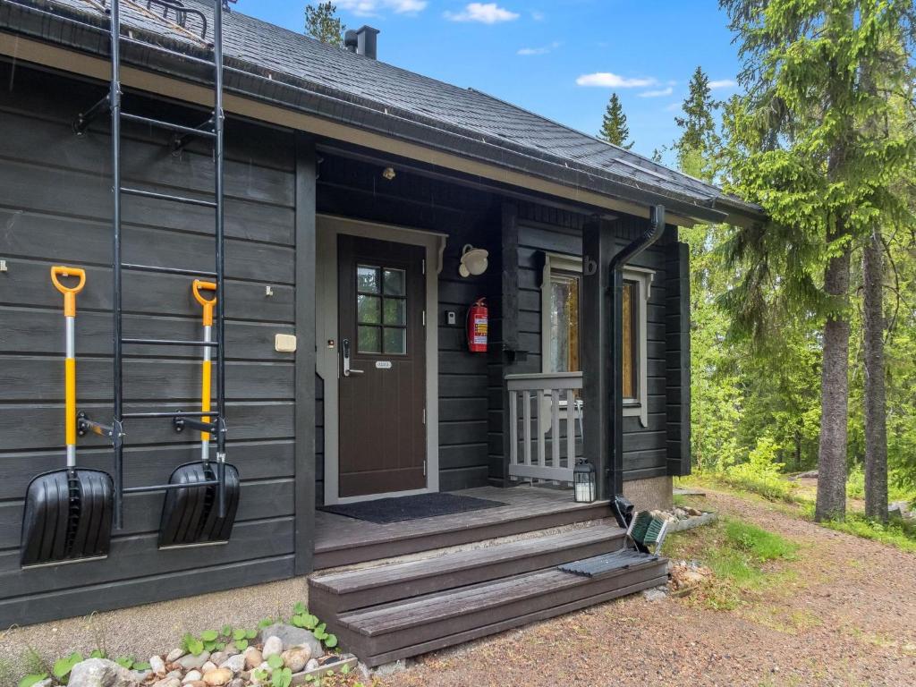 ein schwarzes kleines Haus mit einer Veranda und einer Tür in der Unterkunft Holiday Home Vuokatin alma by Interhome in Vuokatti
