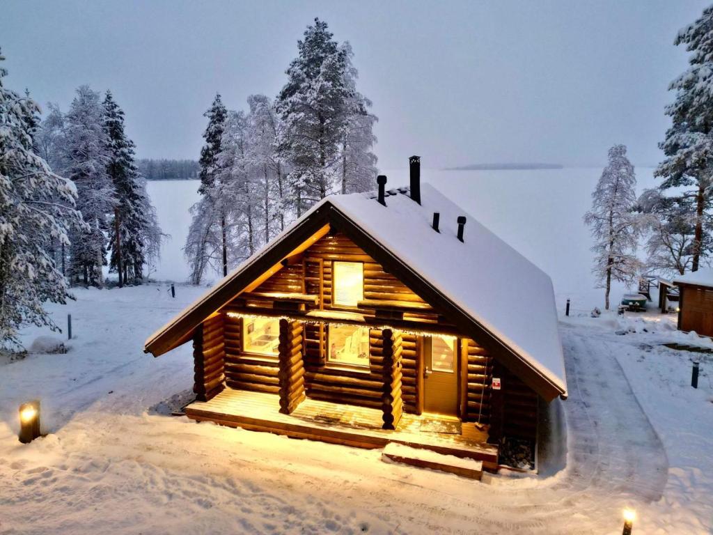 una cabaña de madera en la nieve con luces encendidas en Holiday Home Vanttausranta by Interhome, en Oikarainen