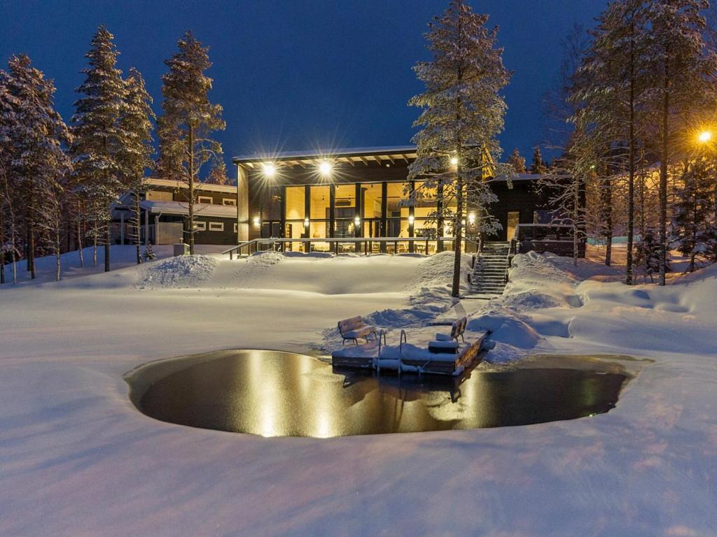 a house with a pond in the snow at Holiday Home Villa uggo by Interhome in Hyrynsalmi