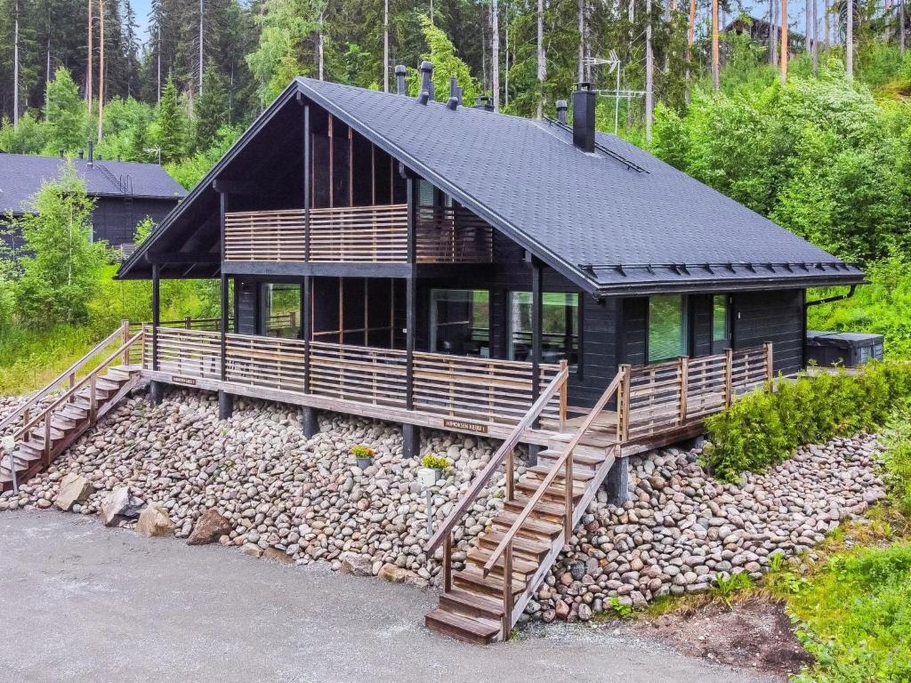 a house with a black roof and a pile of rocks at Holiday Home Himoksen keiju 1 by Interhome in Jämsä